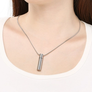 Close-up of minimalist cylindrical steel pendant necklace on a model with snake chain