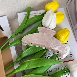 Macro detail of large marble pink acrylic hair claw clip on decorative tulip flowers