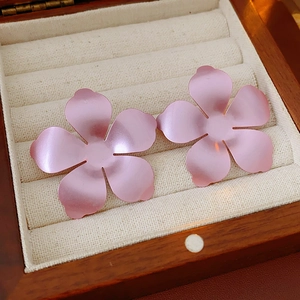 Gros plan de boucles d'oreilles fleurs rose mat dans un coffret à bijoux en bois avec doublure