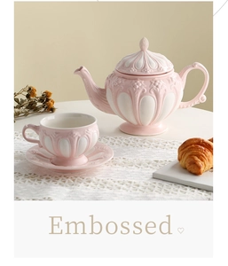 Macro view of vintage pink embossed ceramic teapot with intricate floral relief textures