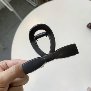 Close-up of a matte black bow-shaped hair claw clip with a strong spring mechanism