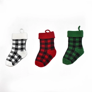 Three knit buffalo plaid Christmas stockings in black, red, and green on white backdrop