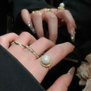 Detailed view of luxury gold rings with pearls and zircons worn on a hand with reflection