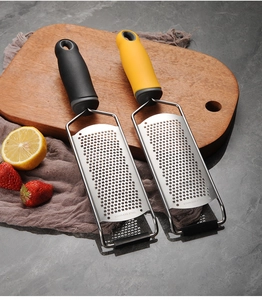 Dual handheld stainless steel cheese graters with lemon on dark wooden board