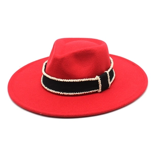Detail of red wool fedora hat featuring a black woven band with white pearl embellishments