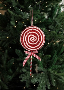 Close-up of glittery red and white spiral lollipop ornament with bow on Christmas tree