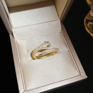 Macro detail of gold plated snake ring with pavé zircons and green gemstone eyes