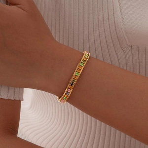 Gold twist chain bracelet featuring a rainbow of multicolored gemstones on a white knit sleeve