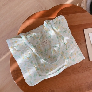 Close-up of floral quilted tote bag with green flower patterns and fabric brand label