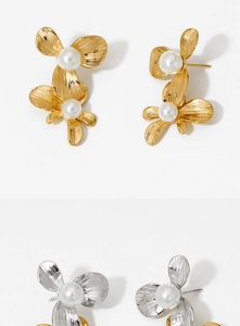 Macro detail of gold and silver flower earrings with elegant white pearl centers