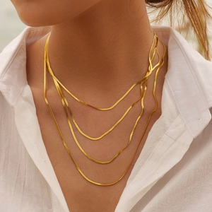 Detail of layered gold snake bone chain necklaces in 5mm blade style on a model