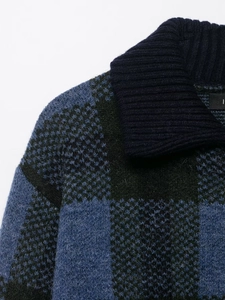 Macro shot of blue and green plaid knit fabric showing fuzzy texture and ribbed collar