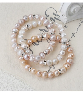 Dettaglio di bracciali di perle naturali d'acqua dolce nei toni bianco, rosa e champagne