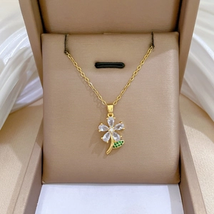 Detail of five-petal flower necklace with clear zircons and green leaf in velvet box