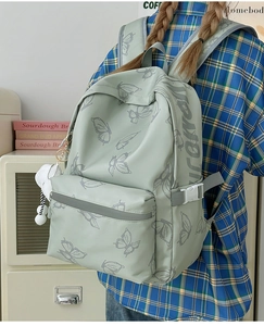 Close-up of light green butterfly backpack with side buckle and plush charm detail