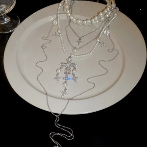 Detailed view of layered pearl necklaces featuring a sparkling diamond cross pendant on a tray