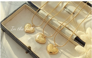 Detailed view of three 18K gold-plated heart necklaces with snake chains in a jewelry box
