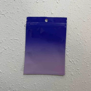 Detailed view of a gradient blue-purple plastic zip bag with a hanging hole on white wall