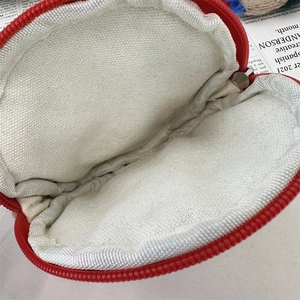 Macro shot of the round red coin pouch showing the white inner lining and metal zipper closure