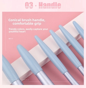 Close-up of light blue conical brush handle with purple metallic ferrule on pink background