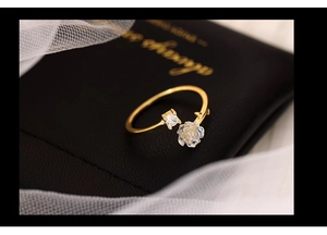 Macro shot of gold-plated rose ring with crystal accent on black leather texture