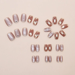 Detail of press-on nails with cat-eye effect, butterfly patterns and rhinestone accents