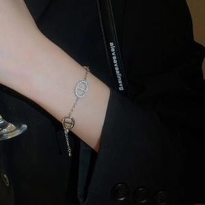 Macro view of double-loop silver bracelet with zircon inlay on a model's wrist