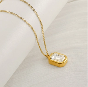 Macro detail of square emerald-cut clear gemstone necklace with gold plated chain