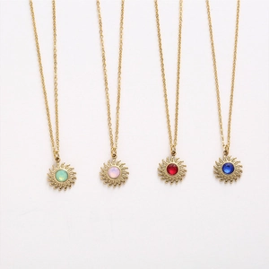 Detail view of four sun pendant necklaces in gold finish with various colored gemstones
