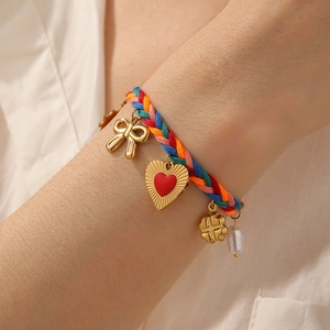 Colorful woven rope bracelet with gold bow, red heart, and pearl charms on wrist