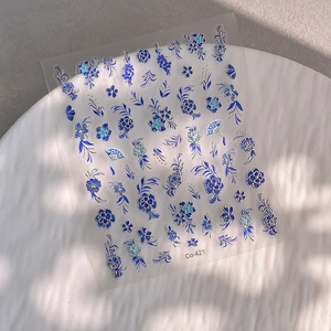 Détail de stickers à ongles gaufrés bleus aux motifs de porcelaine sur assiette blanche