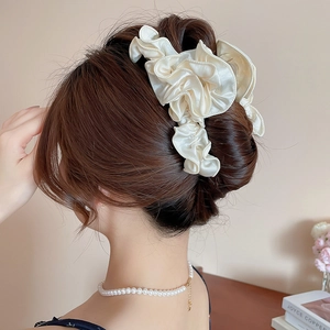 Rear view of model wearing a large cream pleated satin hair claw for elegant updos