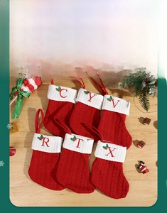 Close-up of red knit Christmas stockings with white cuffs and red embroidered letters