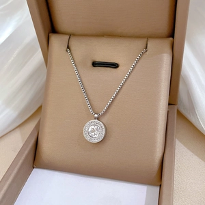 Détail du pendentif cercle argenté serti de pavé et gemme centrale dans une boîte dorée