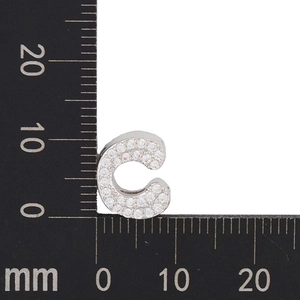 Macro view of C-shaped silver pendant with white zircons, dimensions 12x13mm shown on ruler
