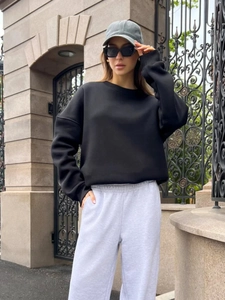 Outdoor street shot of women's oversized black crewneck sweatshirt with grey joggers