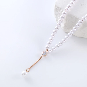 Elegant Y-shaped pearl necklace with sparkling zircon pendant on textured white stone