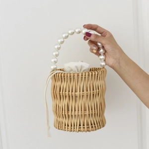 Detail van handgeweven rotan handtas met parelketting en linnen voering met trekkoord