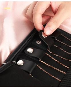 Detail of jewelry organizer featuring snap buttons and rose gold necklaces on black lining