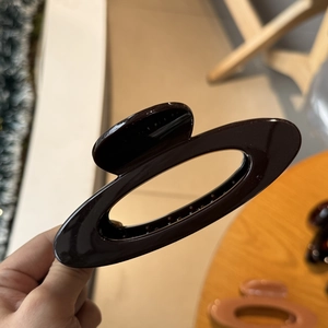 Detailansicht der kaffeebraunen ovalen Haarspange aus elegantem Harzmaterial für Damen
