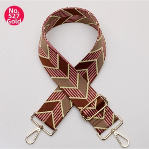Detail of adjustable woven bag strap with pink and brown V-pattern and gold hardware