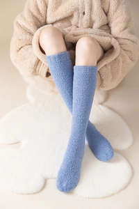 Detail of blue coral fleece over-knee socks showcasing soft plush texture on white fur rug