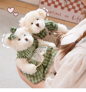 Detail of couple teddy bears in green plaid outfits held by hands in a warm setting