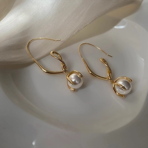 French vintage pearl drop earrings with elegant gold hooks on silk background