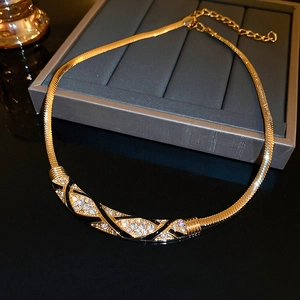 Close-up of golden choker with black enamel patterns and sparkling crystals on jewelry box