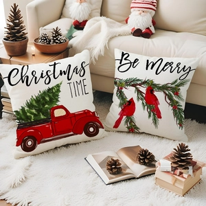 Close-up of linen Christmas pillow covers featuring red truck and festive pine branch patterns