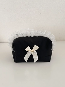 Trousse à maquillage noire avec bordure en dentelle blanche et nœud élégant