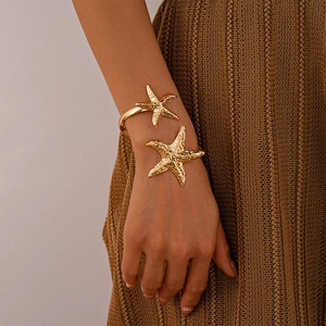 Detail of a textured golden starfish cuff bracelet worn elegantly on a female wrist