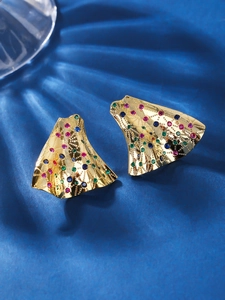 Macro detail of gold fan earrings with multi-colored stones on navy silk fabric