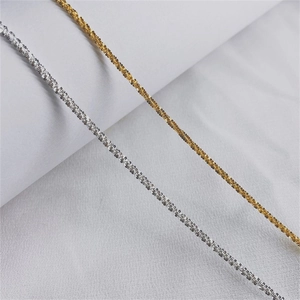Detail shot of delicate gold and silver textured chain bracelets on white fabric